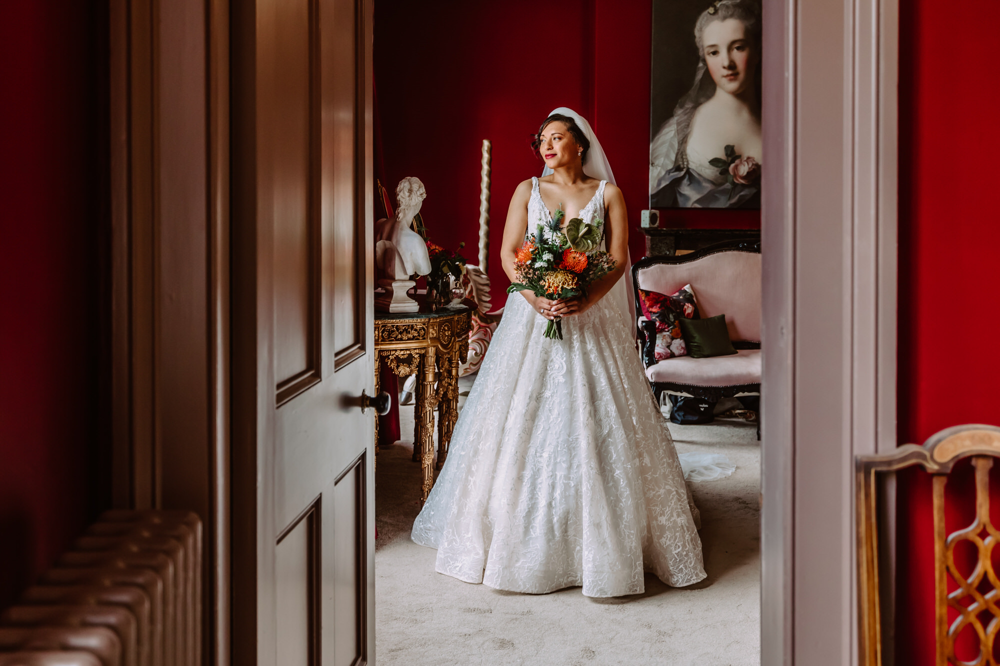 Portrait of bride looking out the window holding bouquet