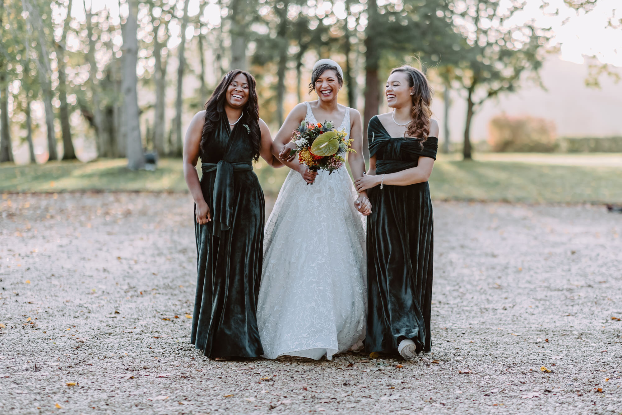 Bride and bridesmaids holding hands laughing while walking towards the camera
