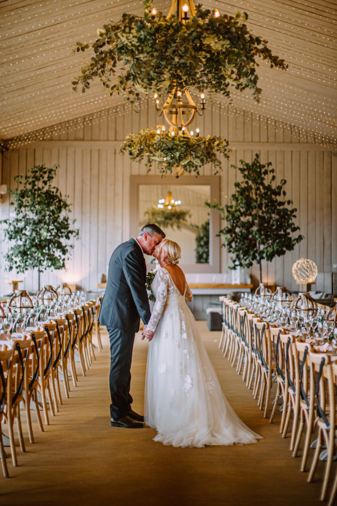 bride and groom kiss during couple portraits in the main barn at Primrose Hill Farm