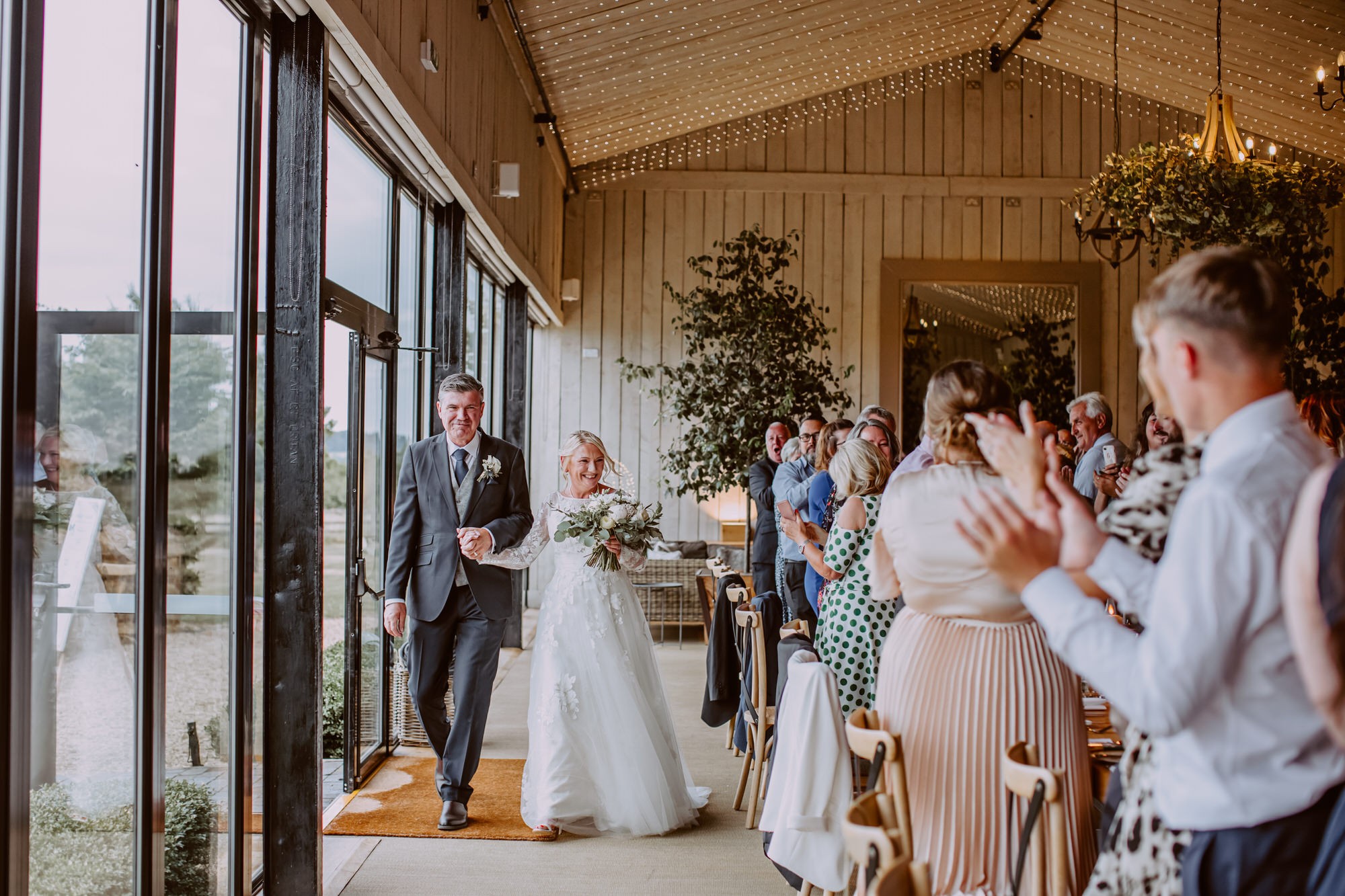 Guests clapping to freshly married couple entering the reception barn at Primrose Hill Farm 