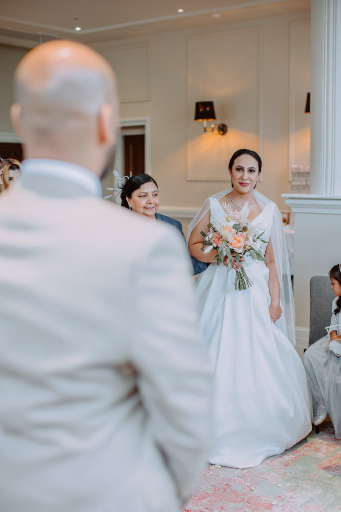 Bride walking down the aisle smiling and looking at groom