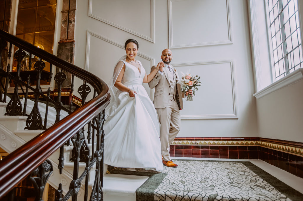 Bride and Groom walking hand in hand down the beautiful staircase of The Grand Hotel Birmingham