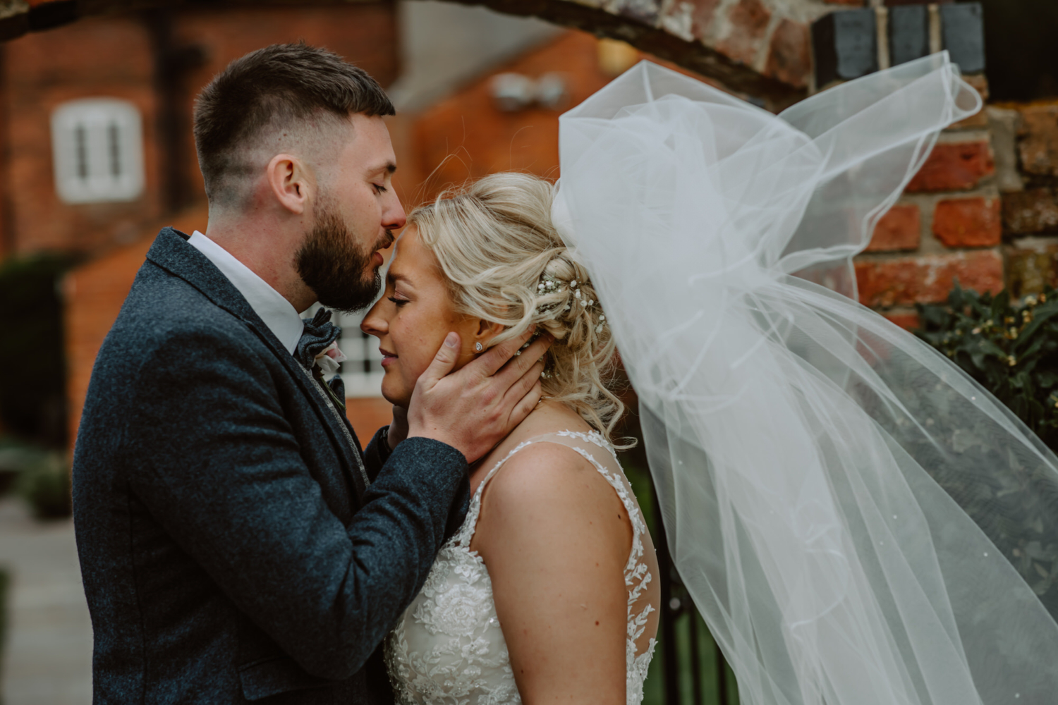 Intimate photo of groom kisses the bride on the forehead 