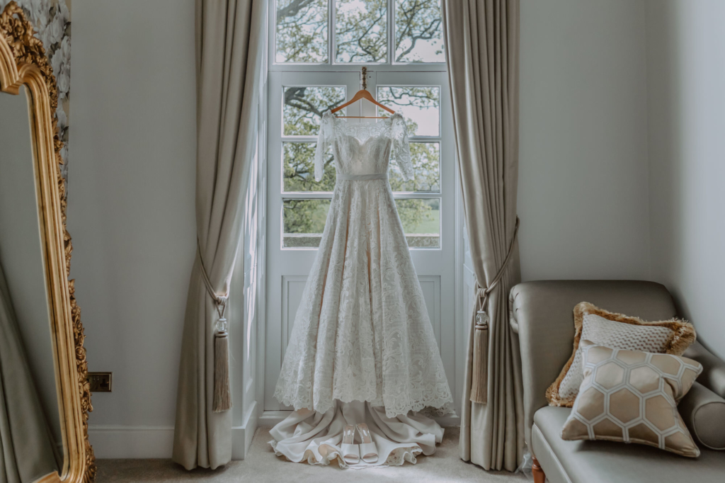 Stunning lace wedding dress hanging on balcony door in dressing room 