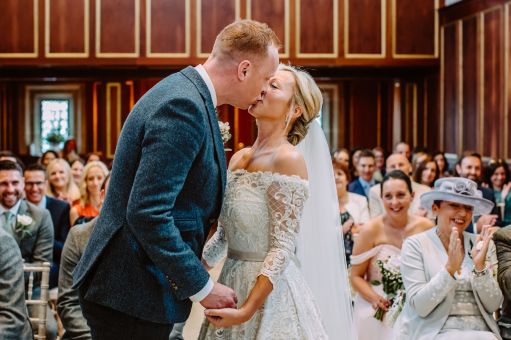 Bride and groom kiss in Catholic Chapen Bourton Hall