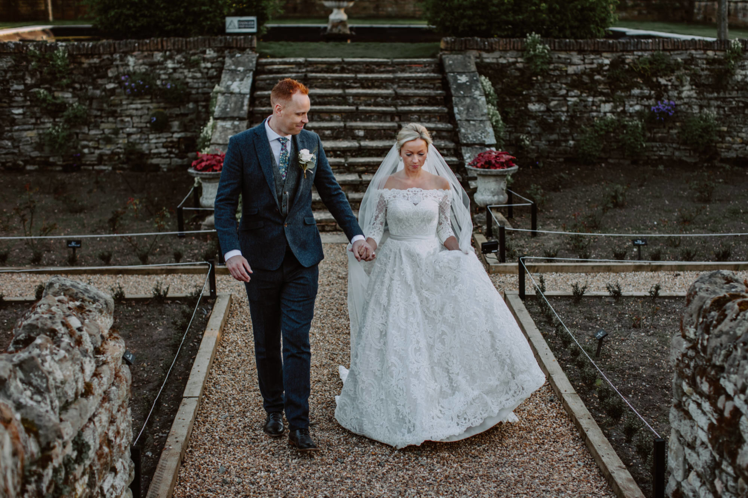 Bride and groom walking through the venue's gardens as Bourton Hall Wedding Photography
