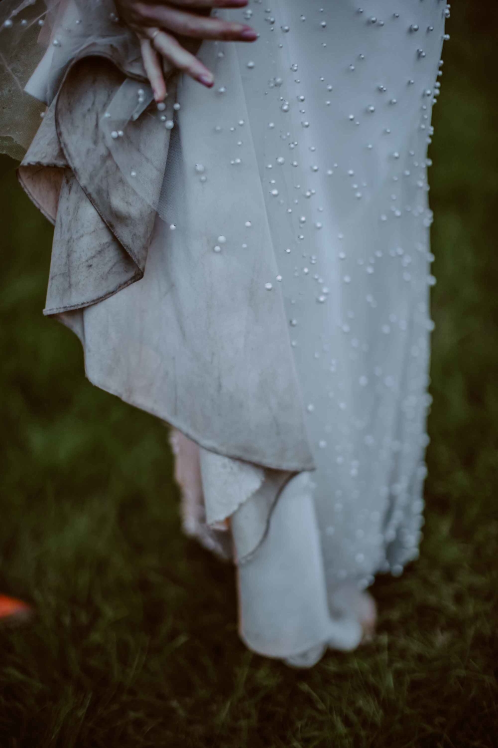 A close-up photo of the bride's dress, showing signs of wear from walking and enjoying the great outdoors during her wedding day photo shoot.