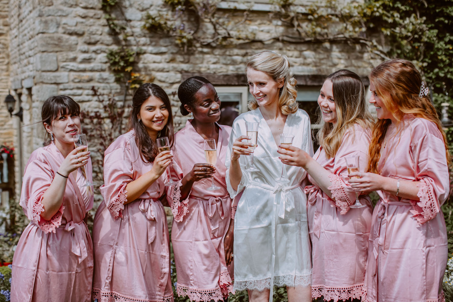 Bride and her bridesmaids group photo in ropes holding a glass of bubbly