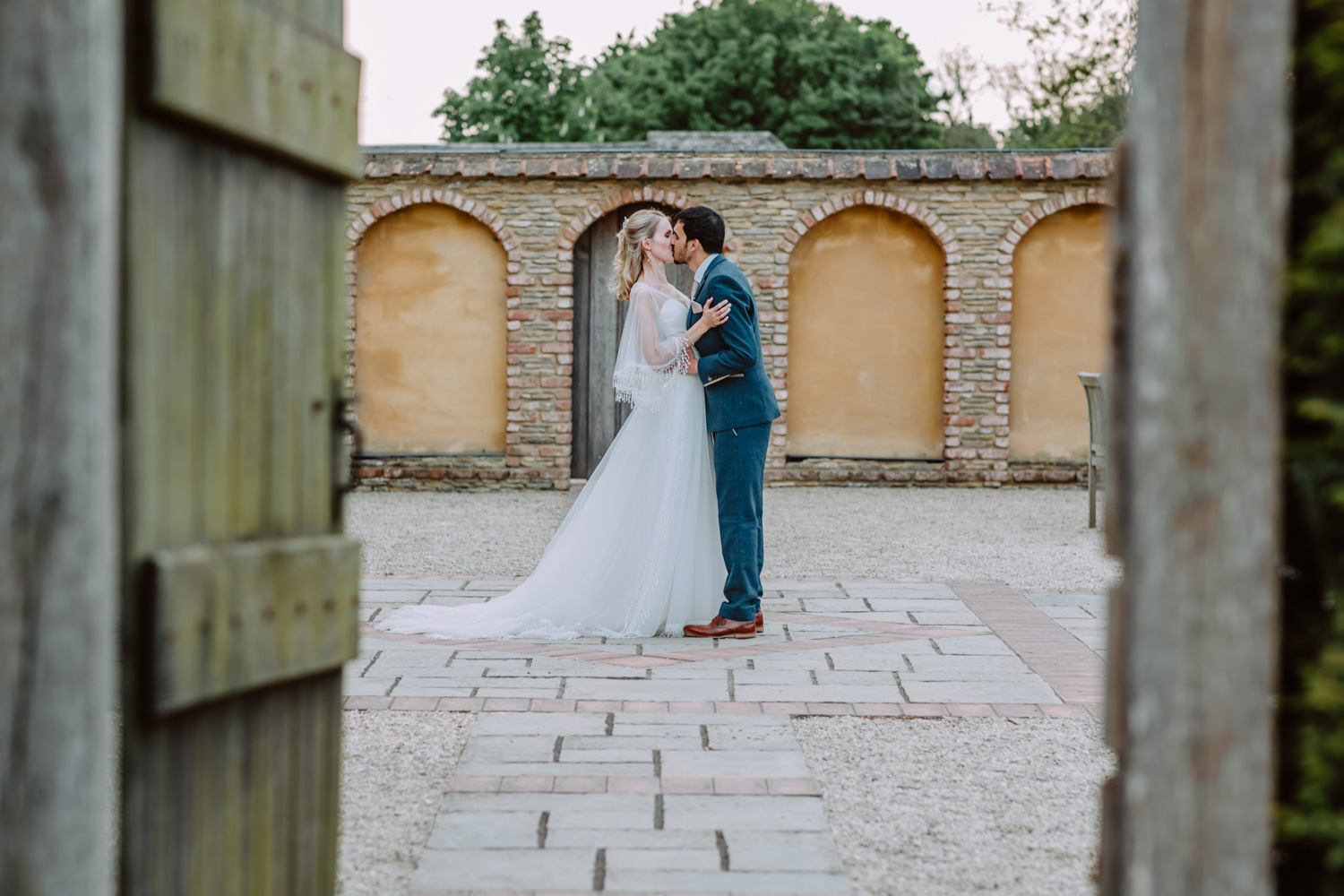 Intimate photo of the bride and groom kiss by the brick wall feature 