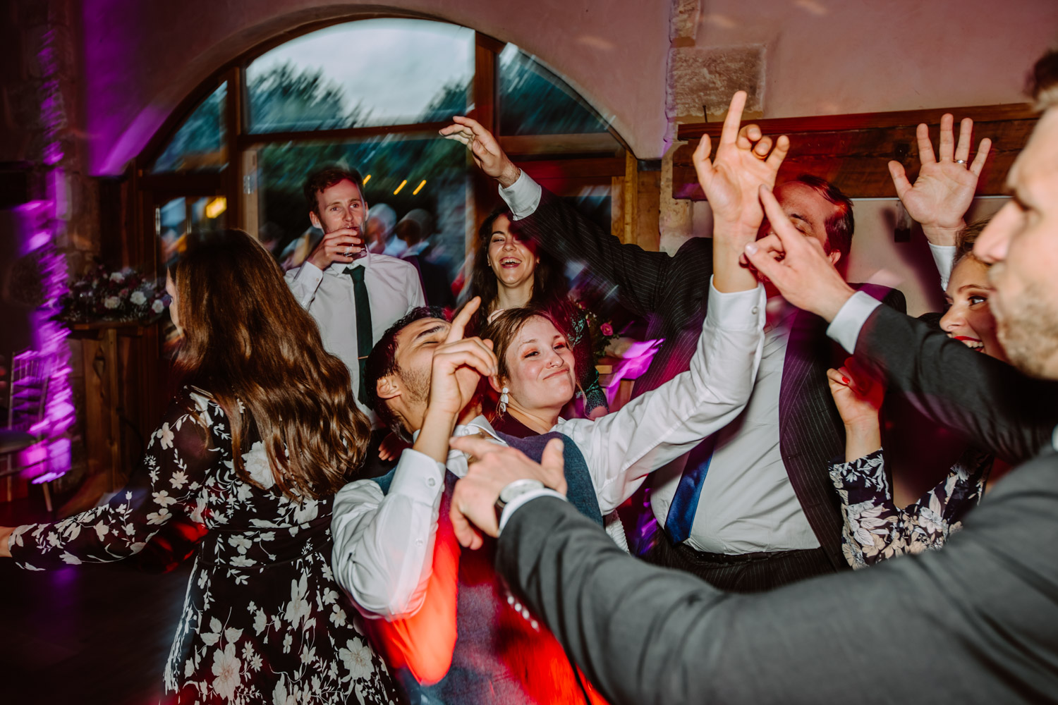 Groom dancing with his friends with his hands in the air 