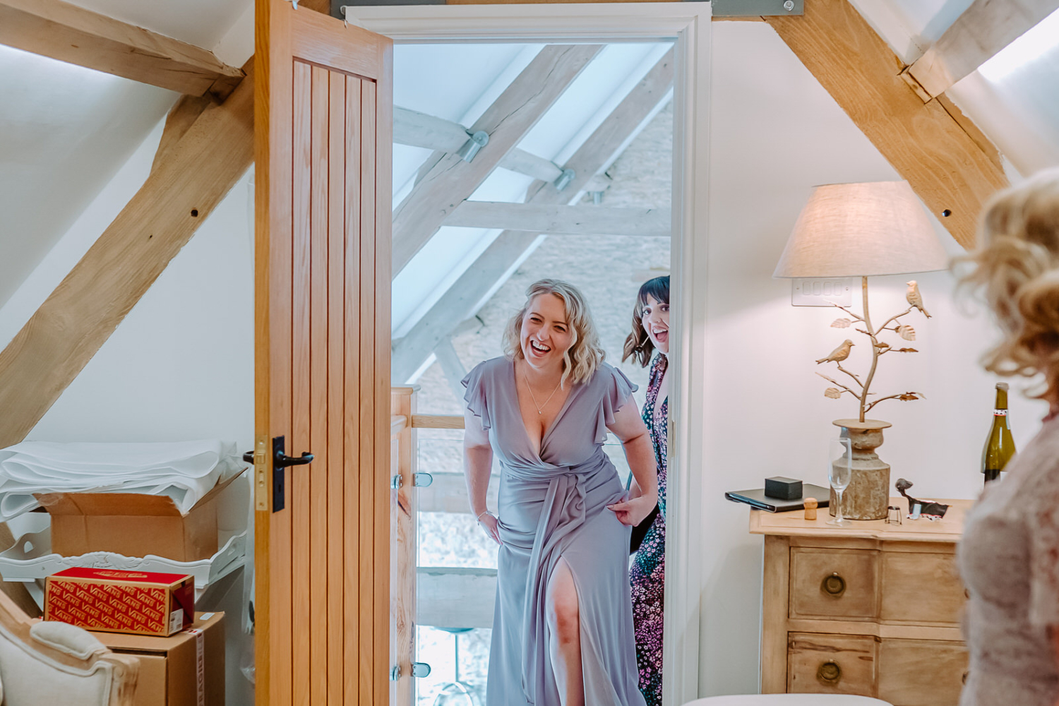 Bridesmaids walks through the door exited to see the bride in her dress 