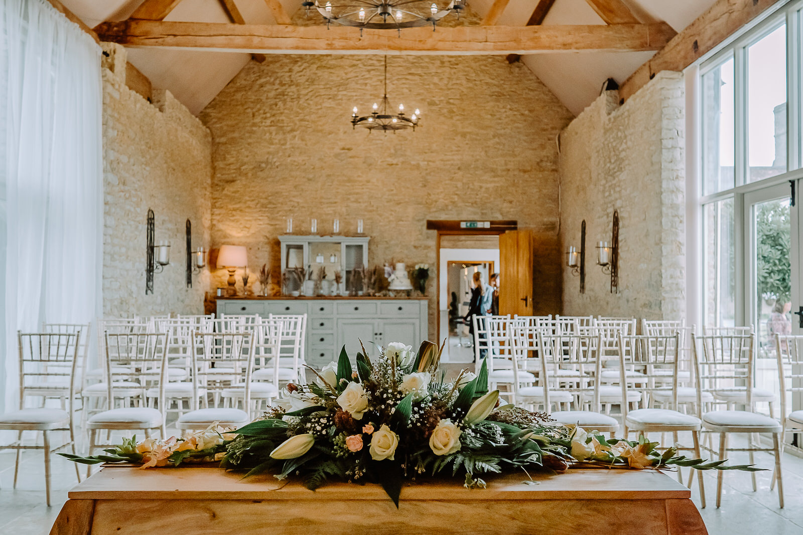 Stratton Court Barn ceremony room with white chairs and flower decoration on the altar