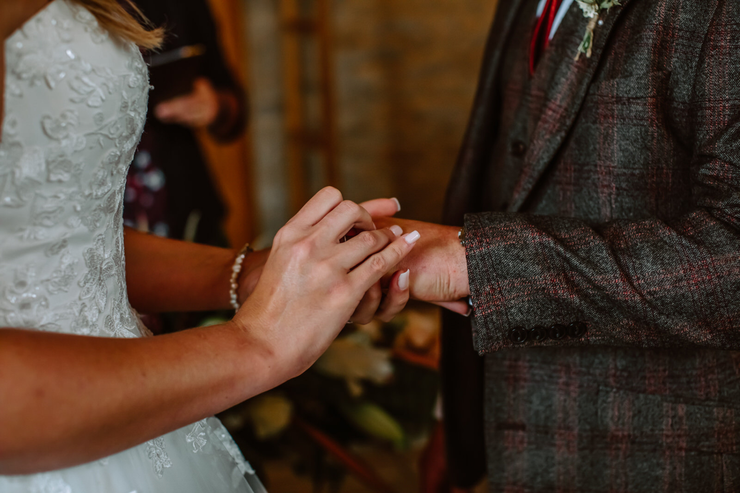Detailed photo of brides hand placing the ring on grooms hand