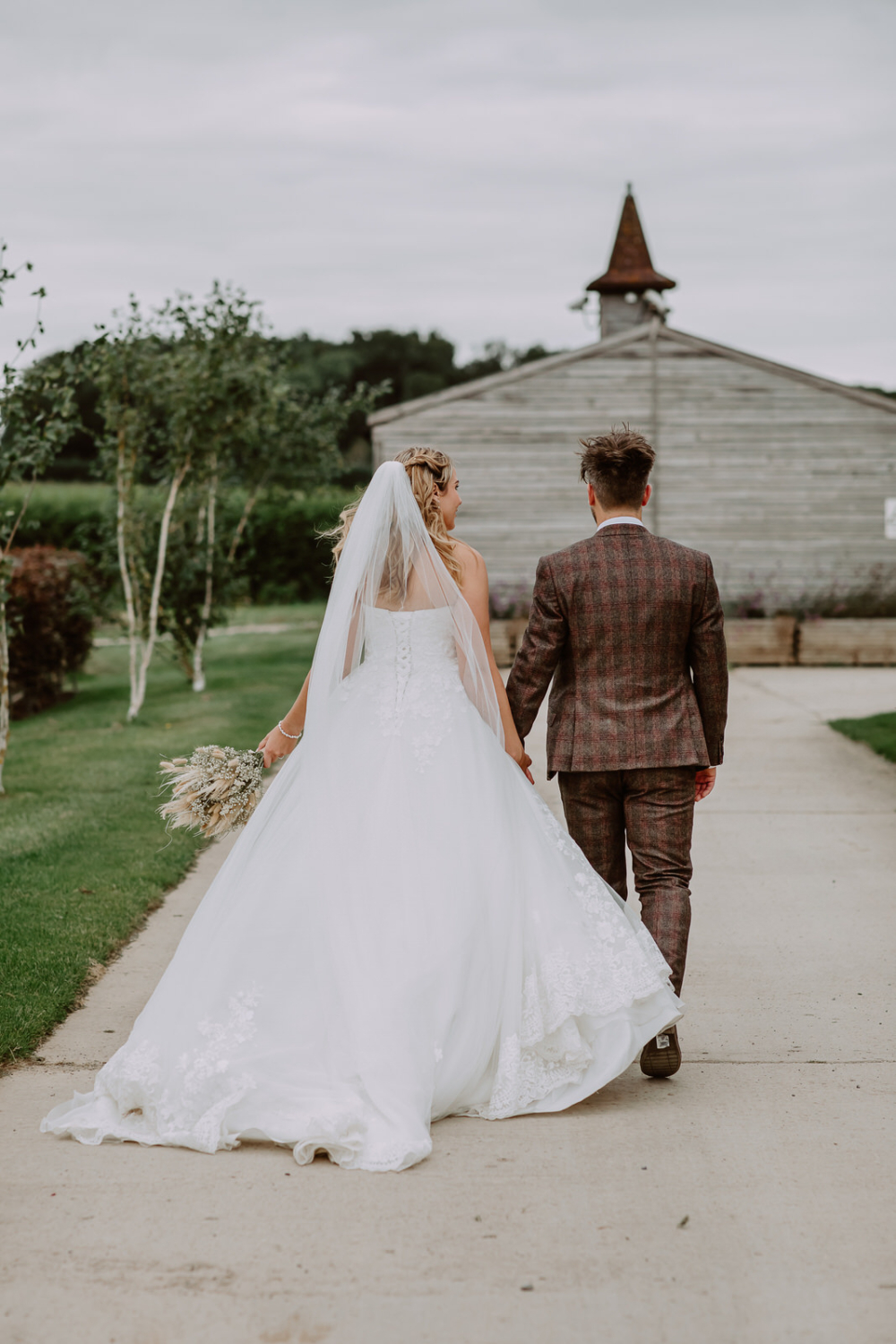 Couple walks away with the wind catching brides dress.