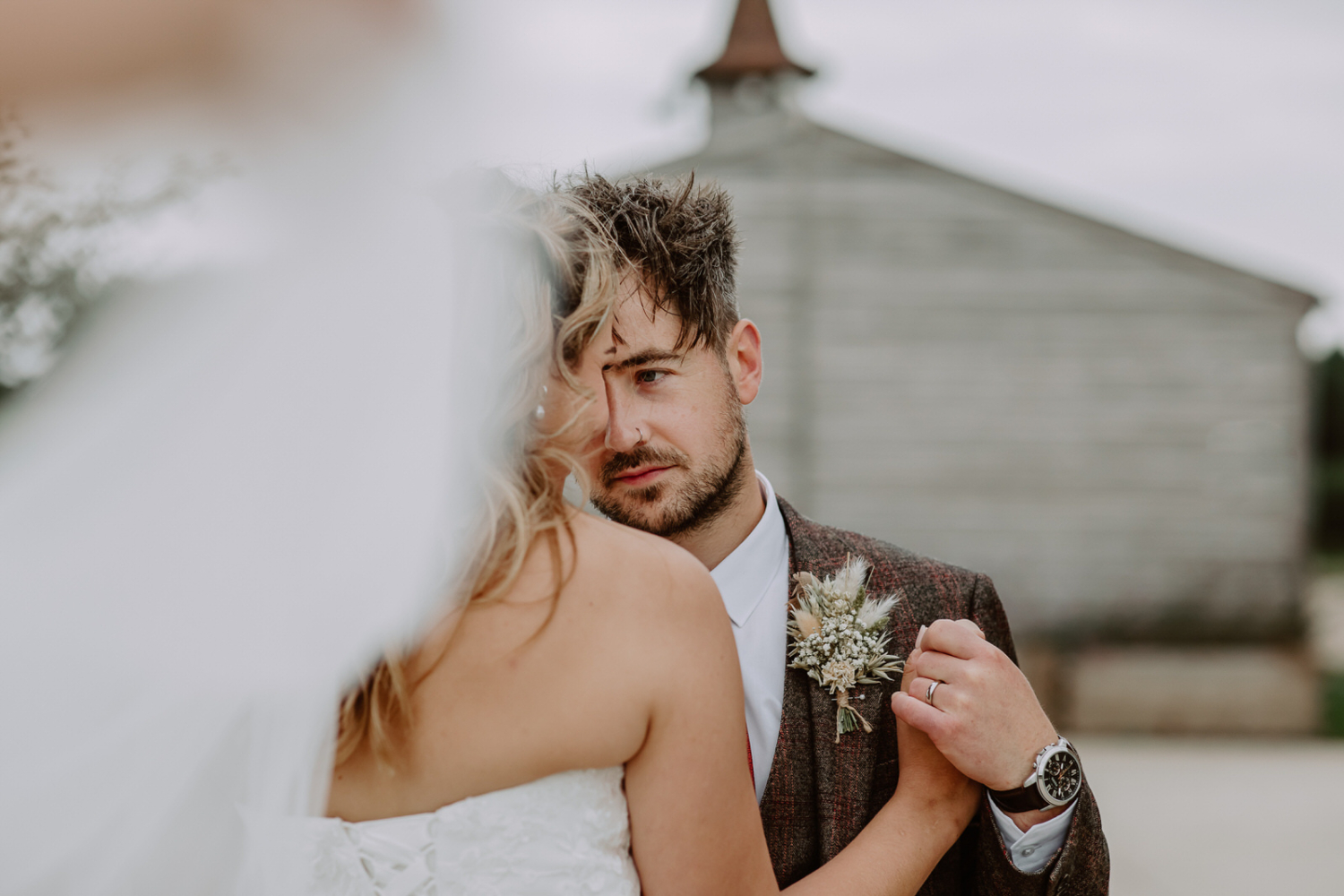 A photo capturing an intimate moment between the bride and groom as they touch their foreheads, with the bride's back facing the camera.