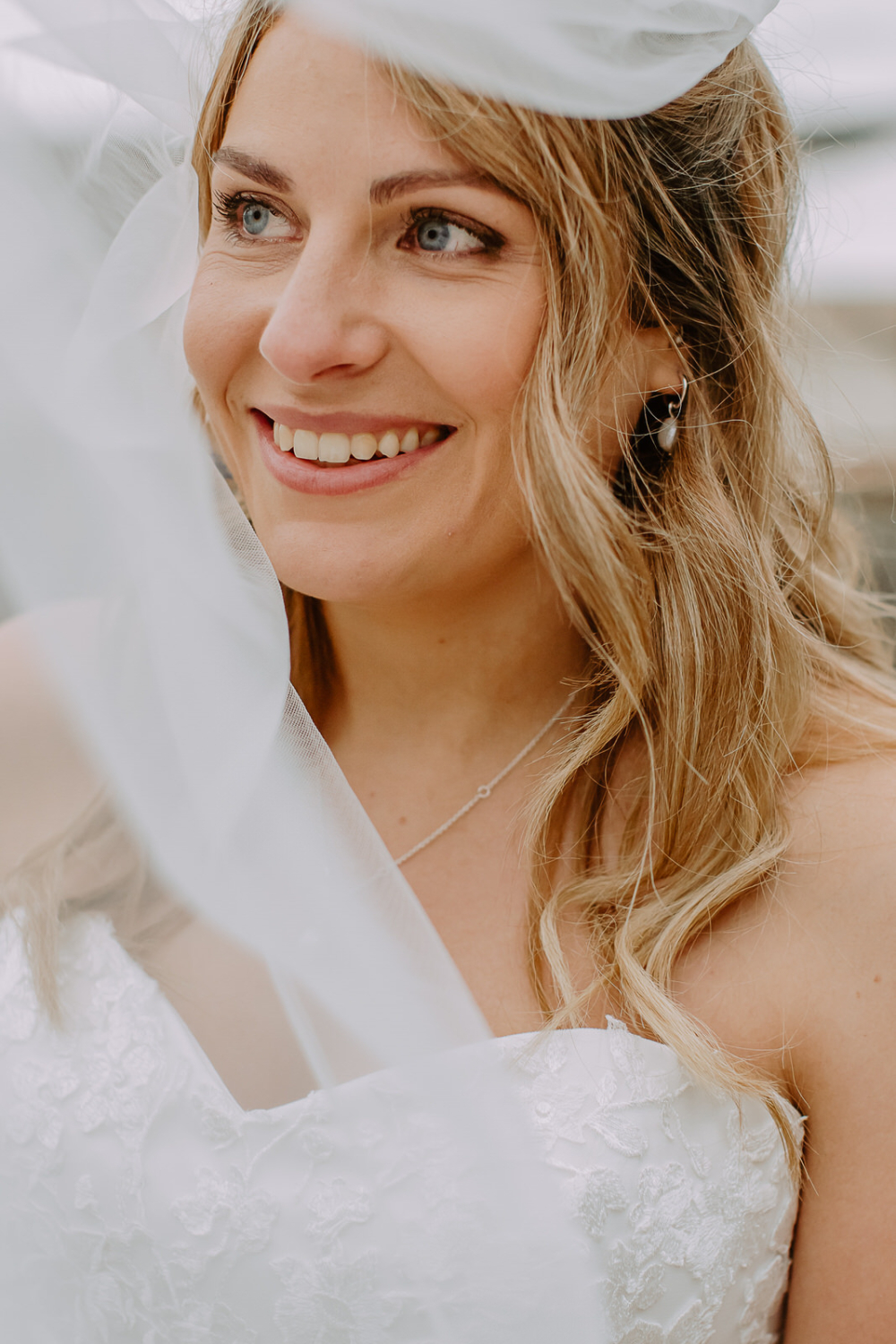 Close portrait of bride with floating veil around her face.