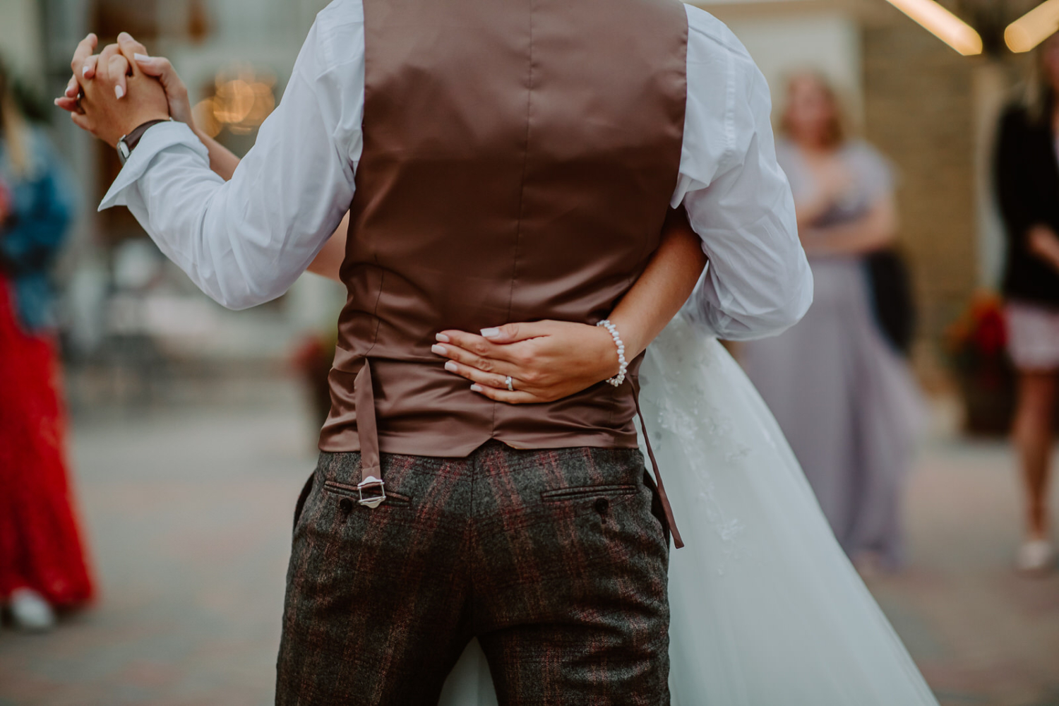 Detailed photo of the bride's hand holding the groom around the waist 