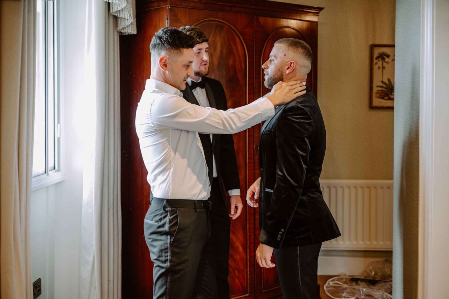 Best man makes sure that the groom looks perfect on his tuxedo