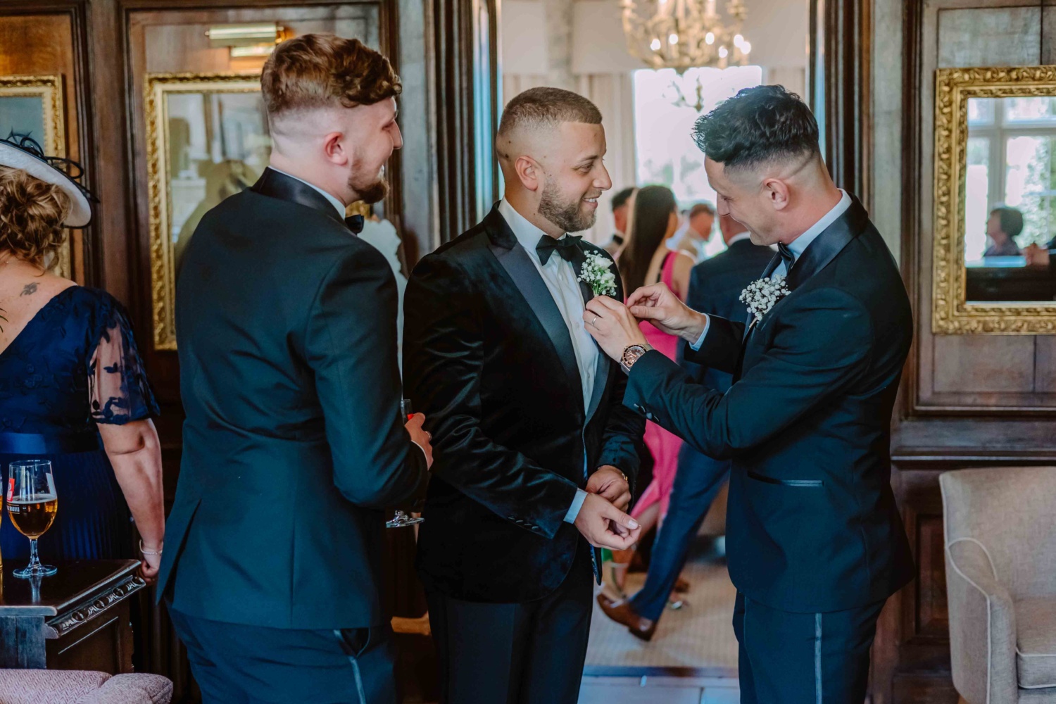 Best men fastening the buttonhole for the groom.