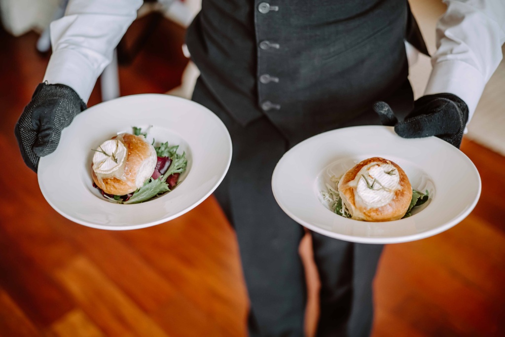Detail photo of the waiters hands holding plates with starters.