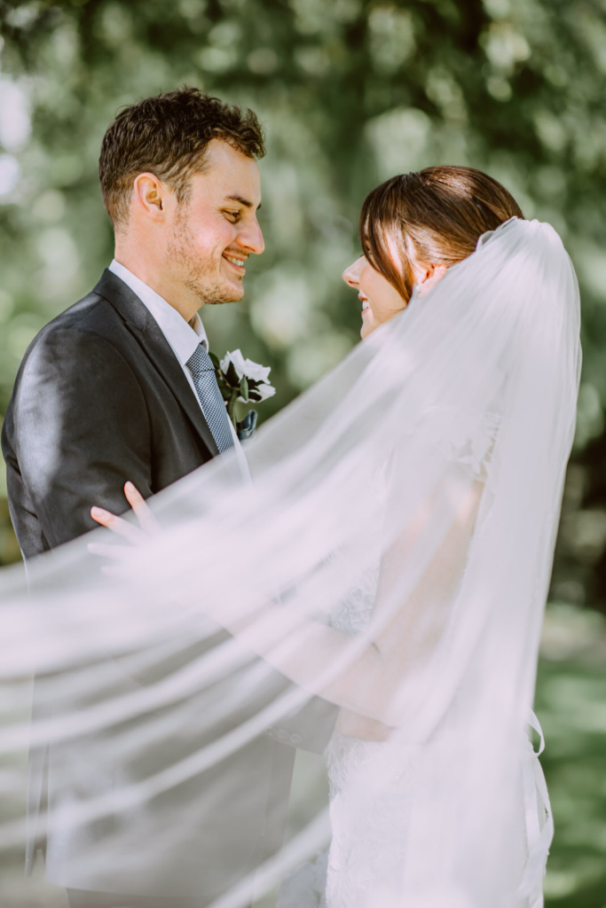 A bride and groom looking at each other through a veil.