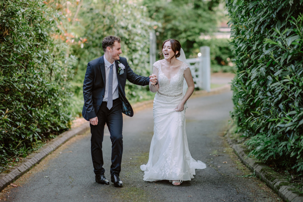 A bride and groom walking down a path in a garden.