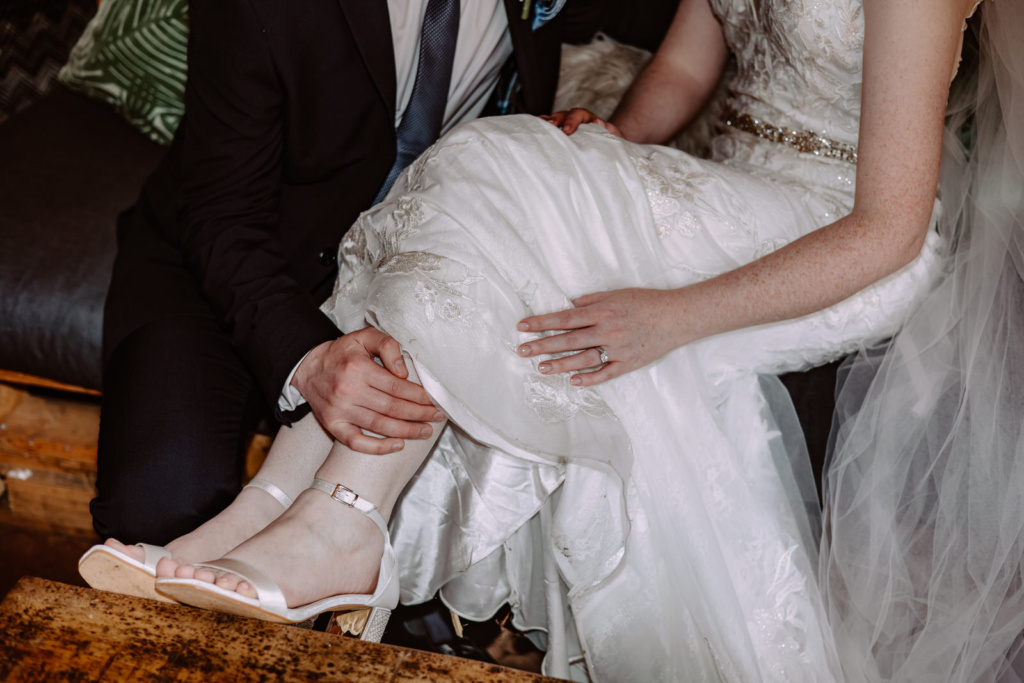 A bride and groom sitting on a couch.