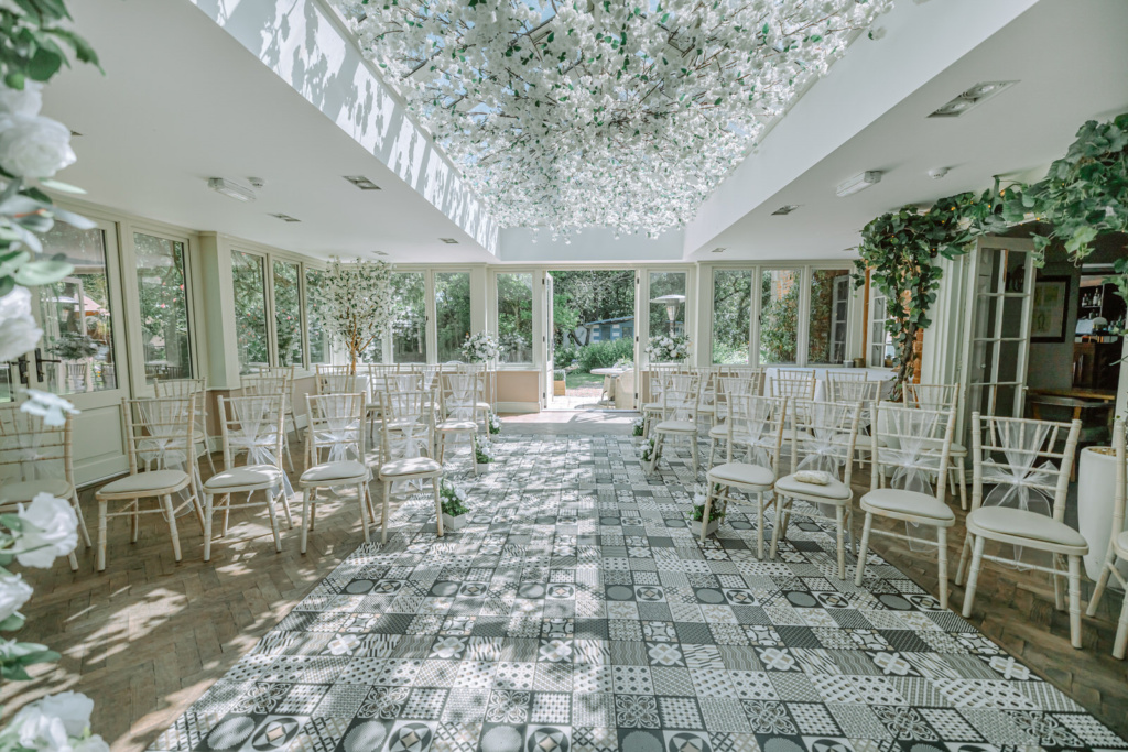 A wedding ceremony set up in a room with flowers and greenery.