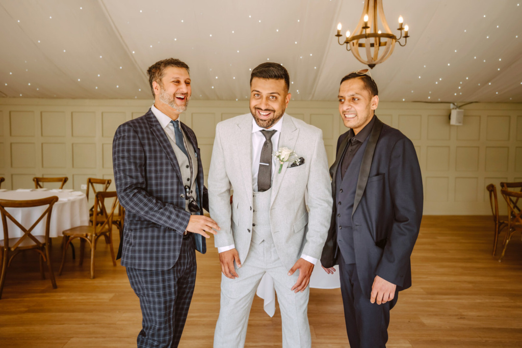 The groom and the groomsmen in suits standing together in a room.