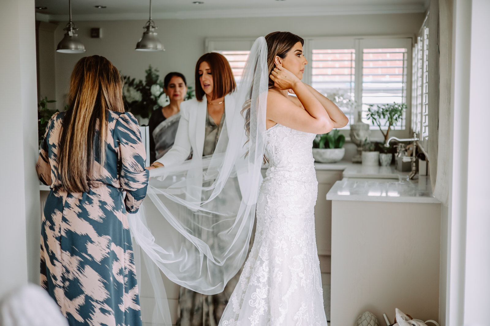 A bride getting ready in a bathroom with her bridesmaids.