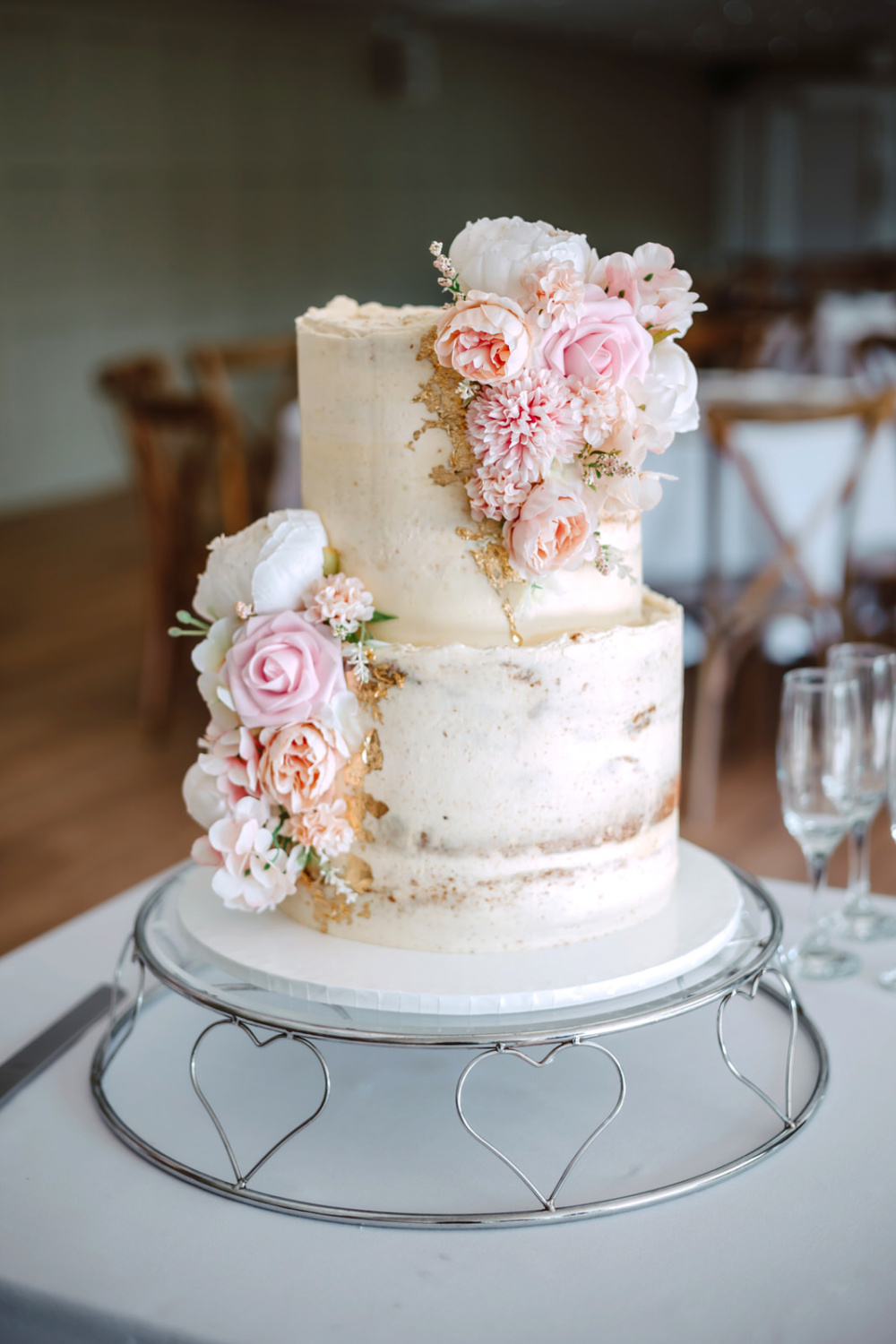 A three tier wedding cake with pink and white flowers.