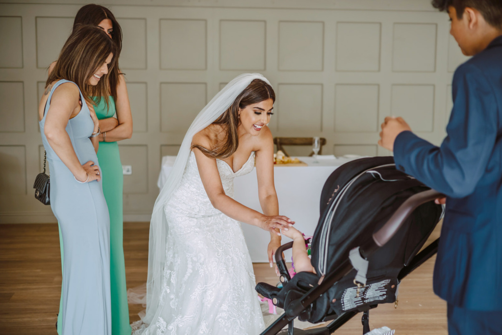 A bride playing with a  baby in a pushchair.