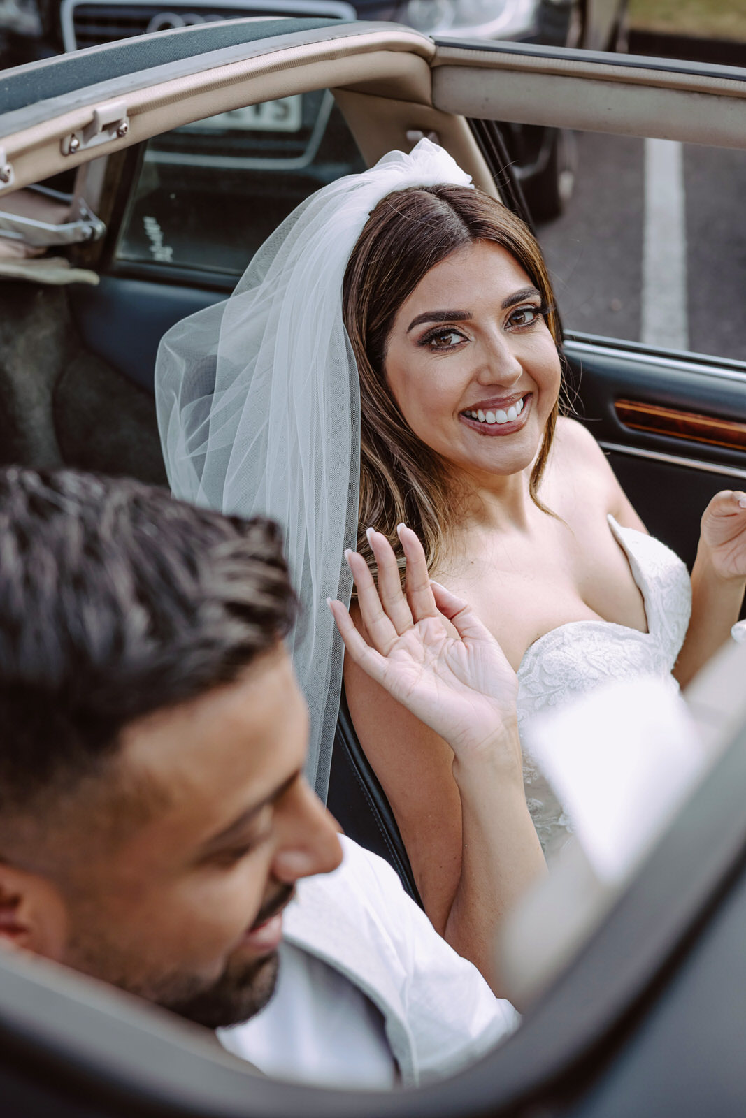 A bride and groom sitting in the back seat of a car.