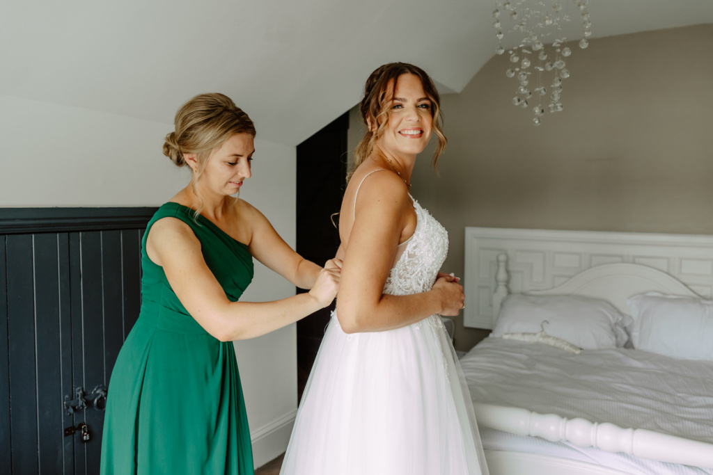 A bridesmaid helping the bride into her wedding dress.