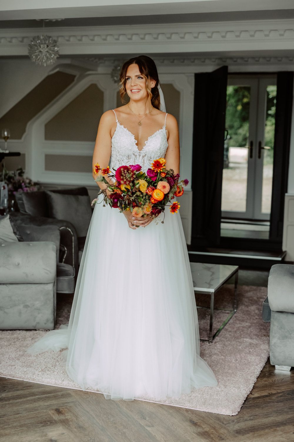 A bride in a wedding dress standing in a living room.