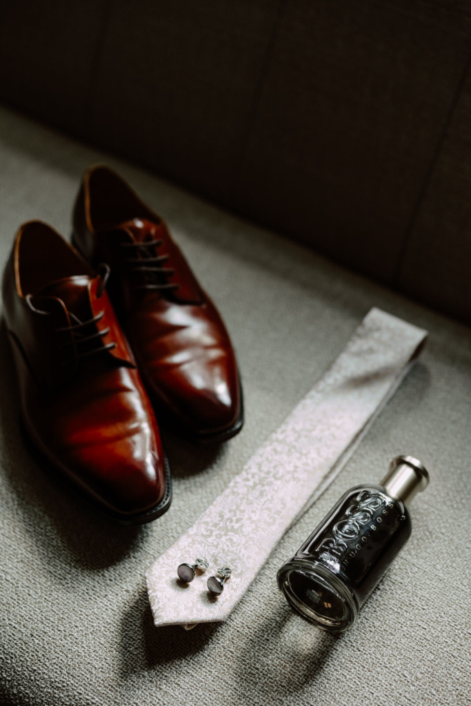 A pair of brown shoes, a tie and a bottle perfume.