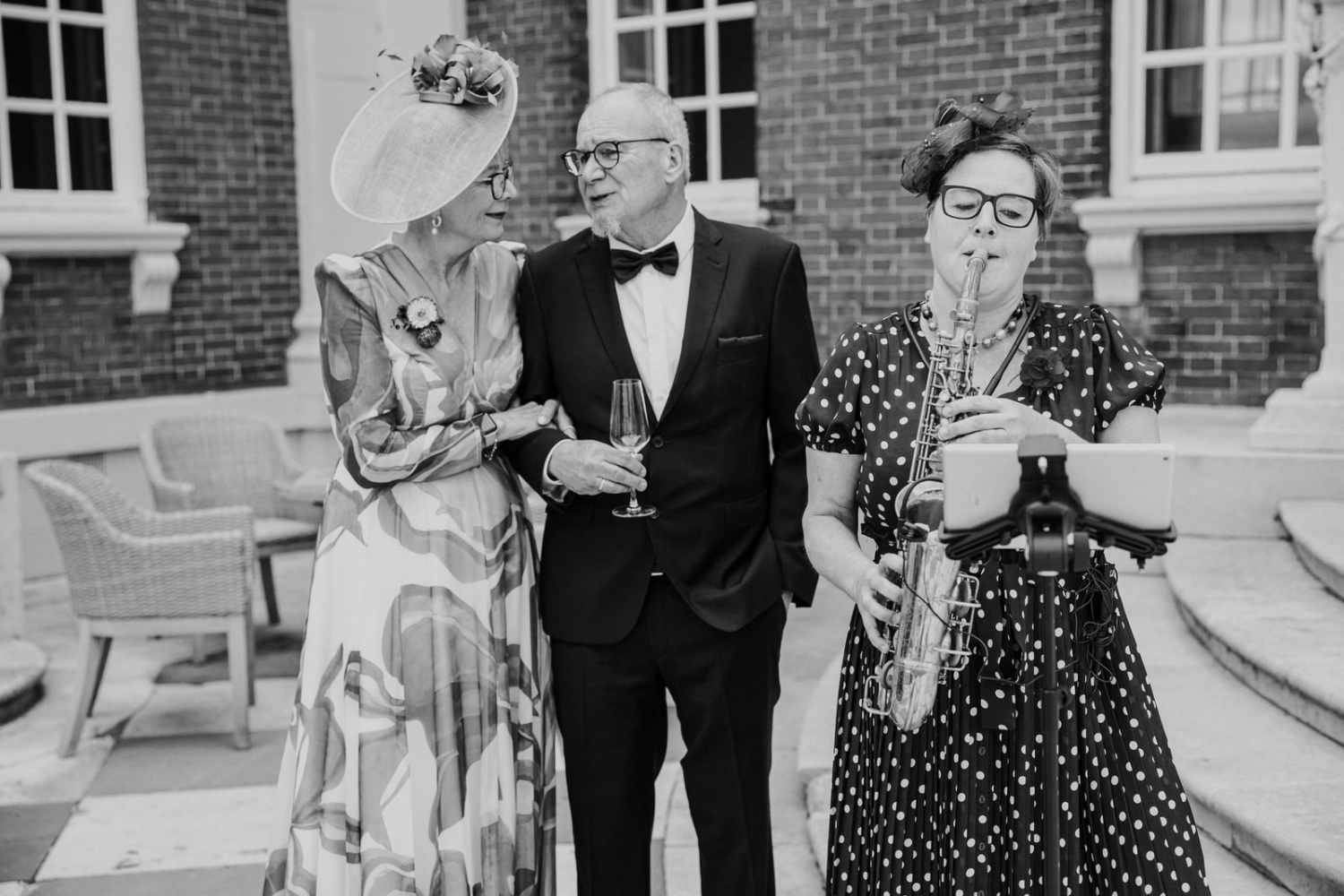 A black and white photo of a woman in a dress and a man with a saxophone.