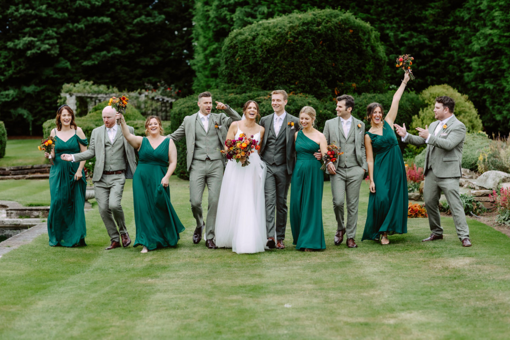 A group of bridesmaids and groomsmen in emerald green dresses.
