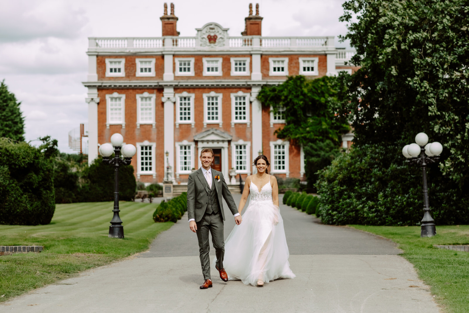 A bride and groom walking in front of a Swinfen Hall.