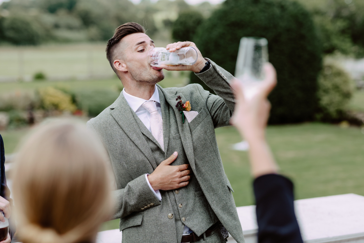 A man in a suit drinking beer from a glass.