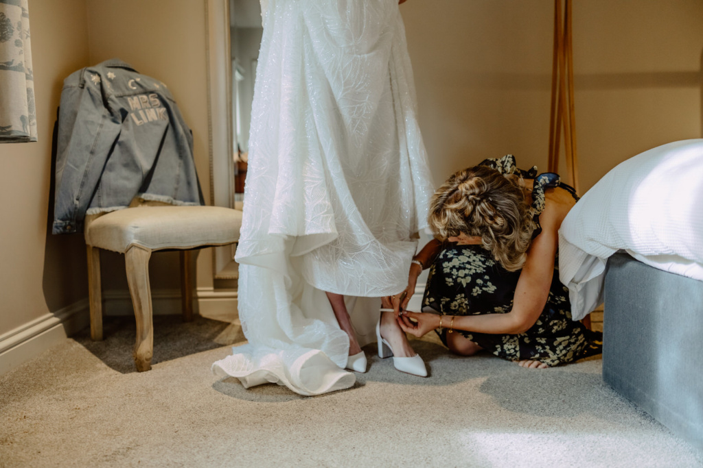 A bride putting on her wedding shoes in a room.