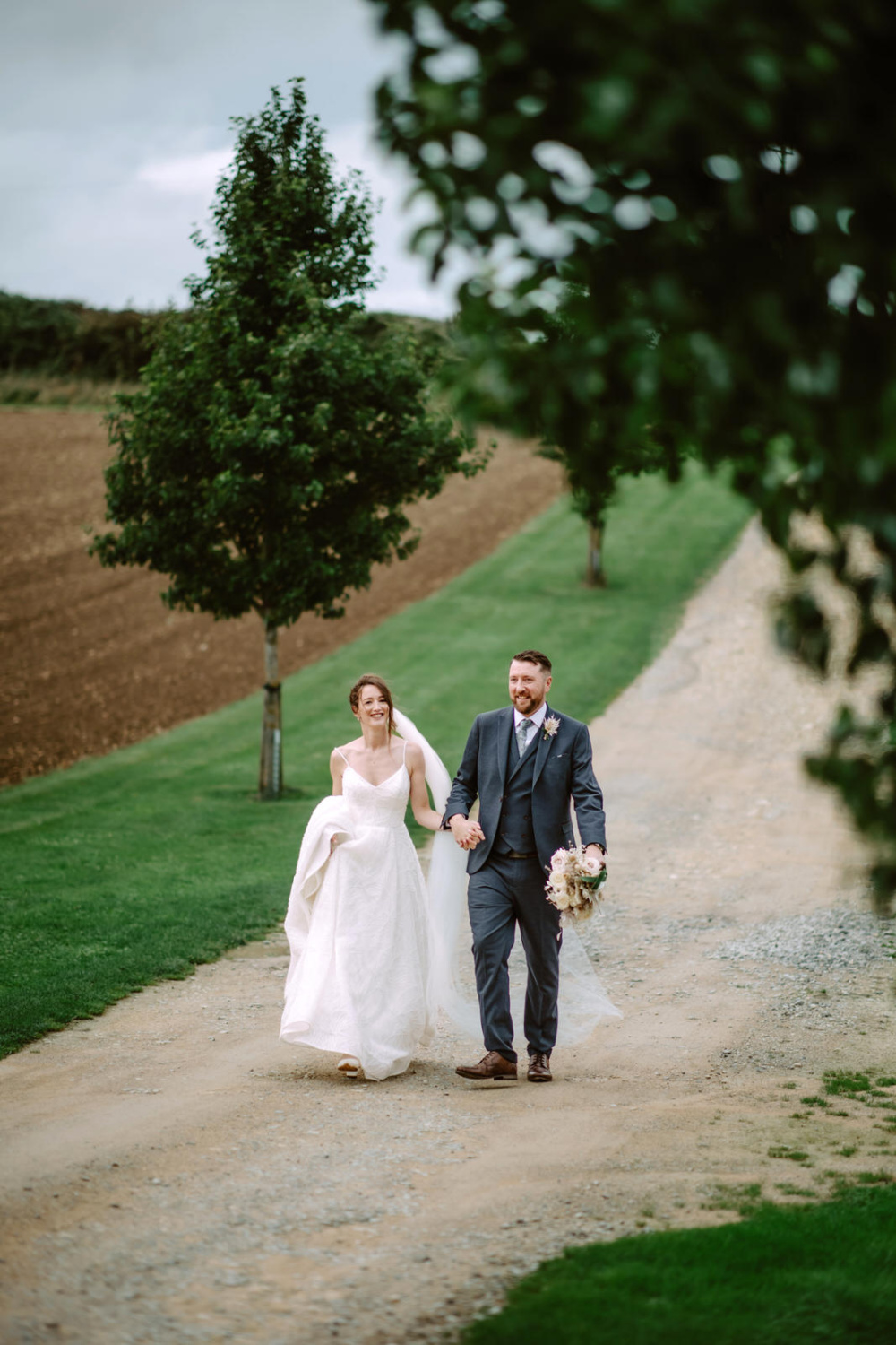 A bride and groom walking down the countryside road.