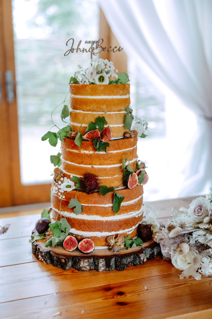 A wedding cake with figs and flowers on top.