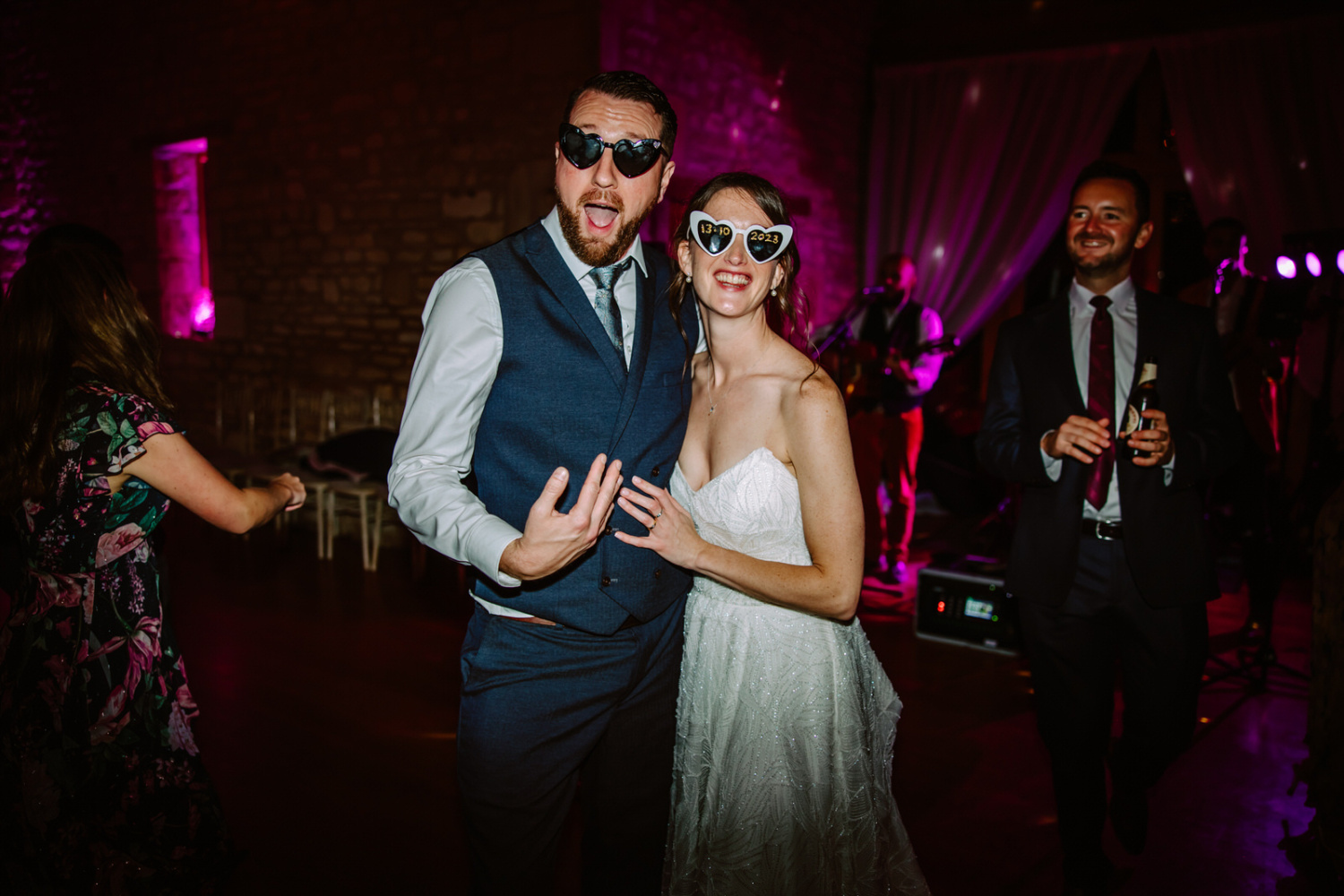 The Bride and groom with heart shaped sunglasses dancing on the dance floor at a party.
