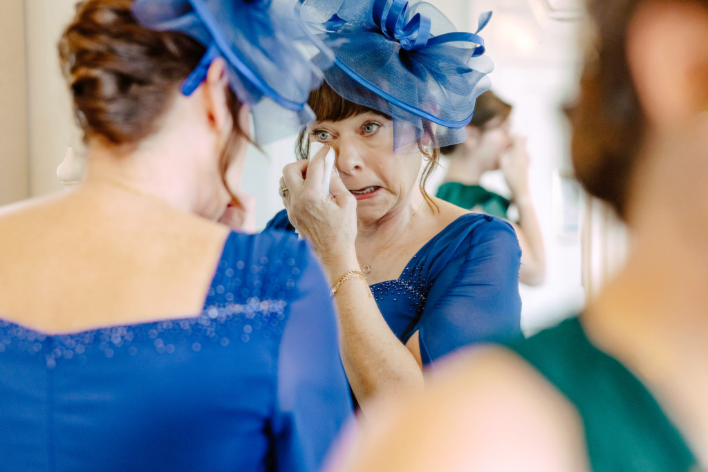 A woman is getting ready in a blue dress and hat.