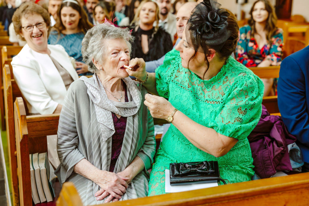 A woman is getting her teeth brushed by an older woman in a church.