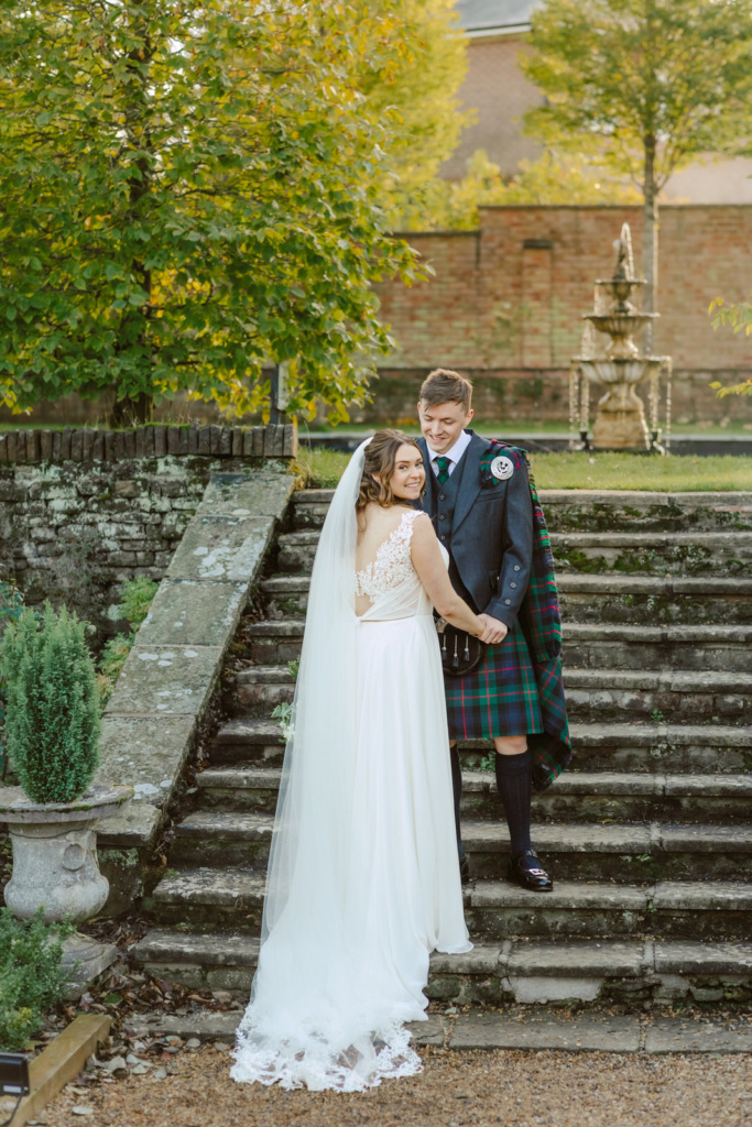 A bride and groom posing on the steps of a Bourton Hall
