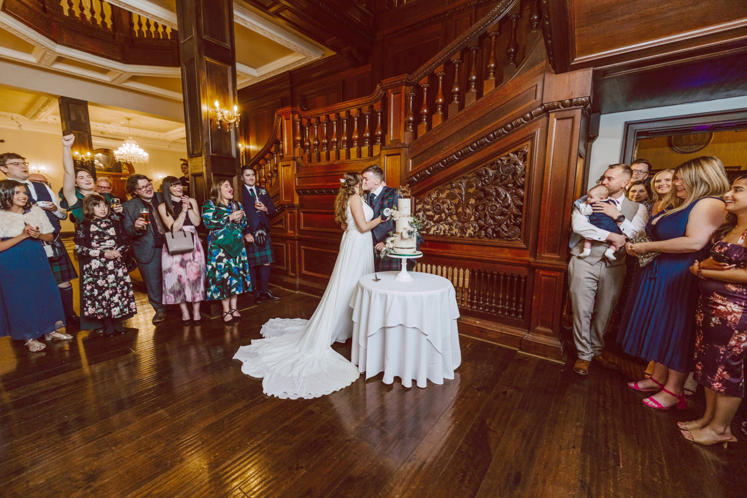 A bride and groom cutting their wedding cake in an ornate room in Bourton Hall