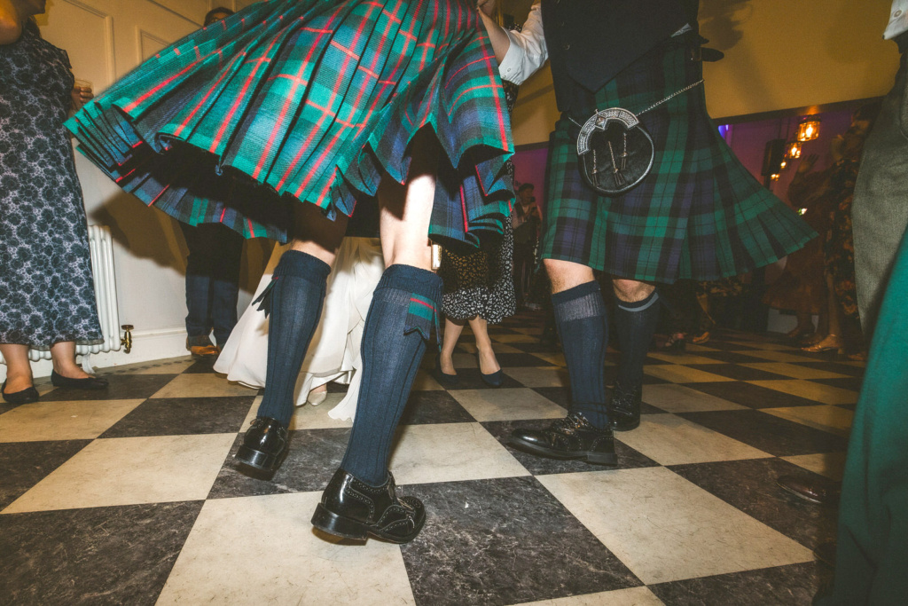 A group of people in kilts dancing at a party.