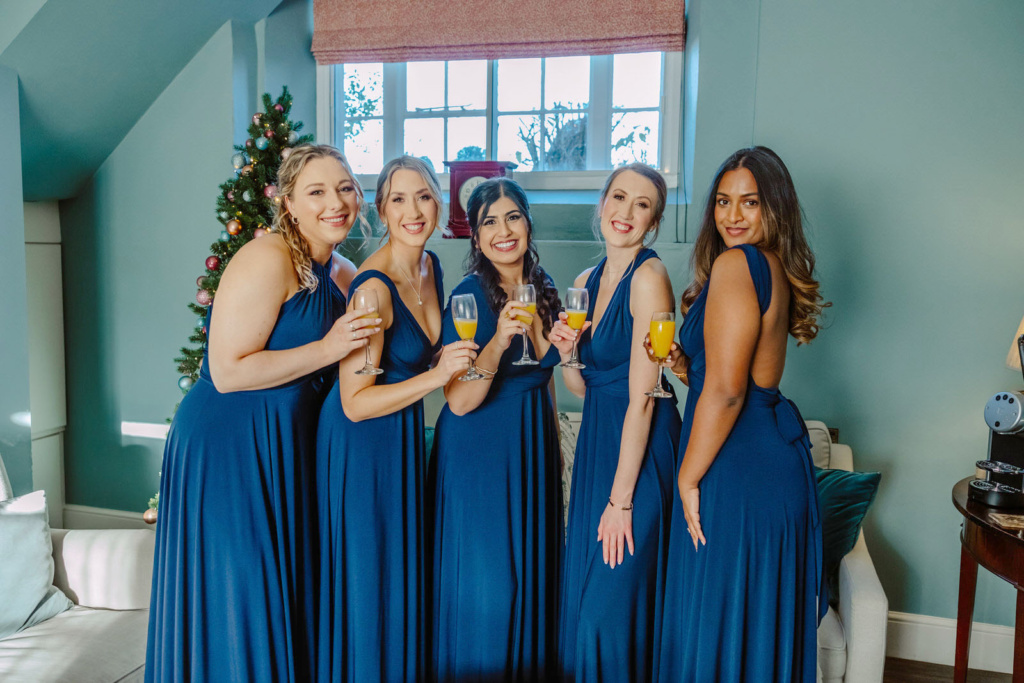 Bridesmaids in blue dresses holding champagne glasses.